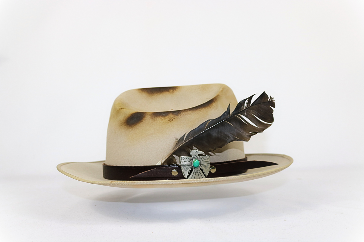 Beige hat with feather and decorative band on a white background