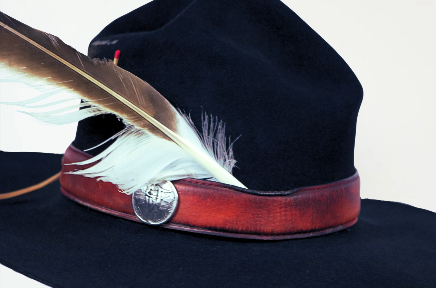 Black hat with red band and feather on a white background