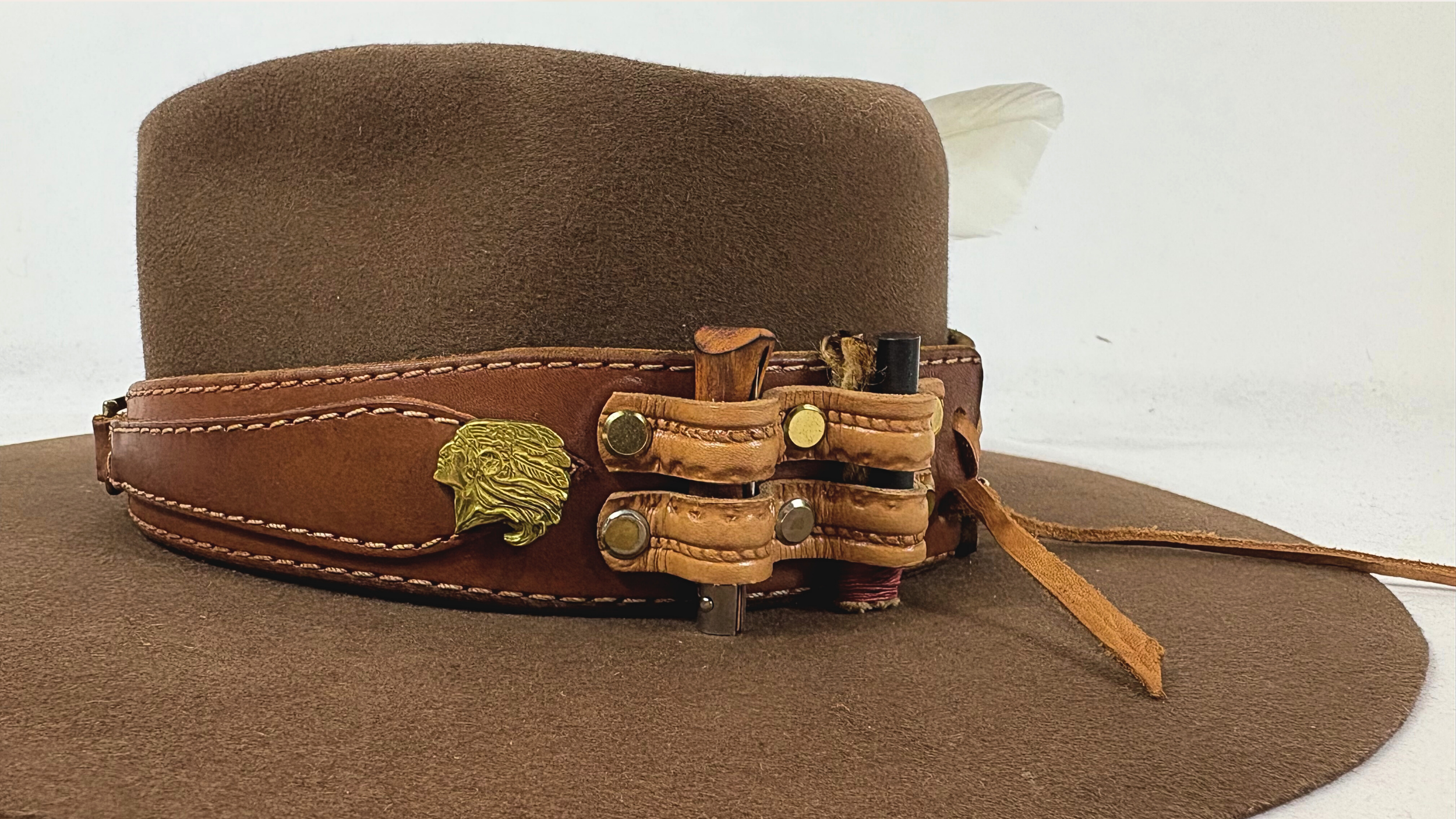 Brown hat with leather band and feather on a white background