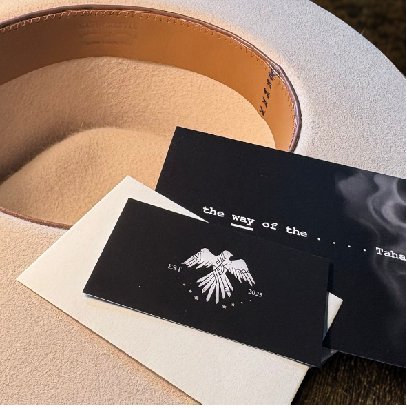 Black card with white text and logo on a beige surface. showing inside of tahatan hat with natural leather sweatband