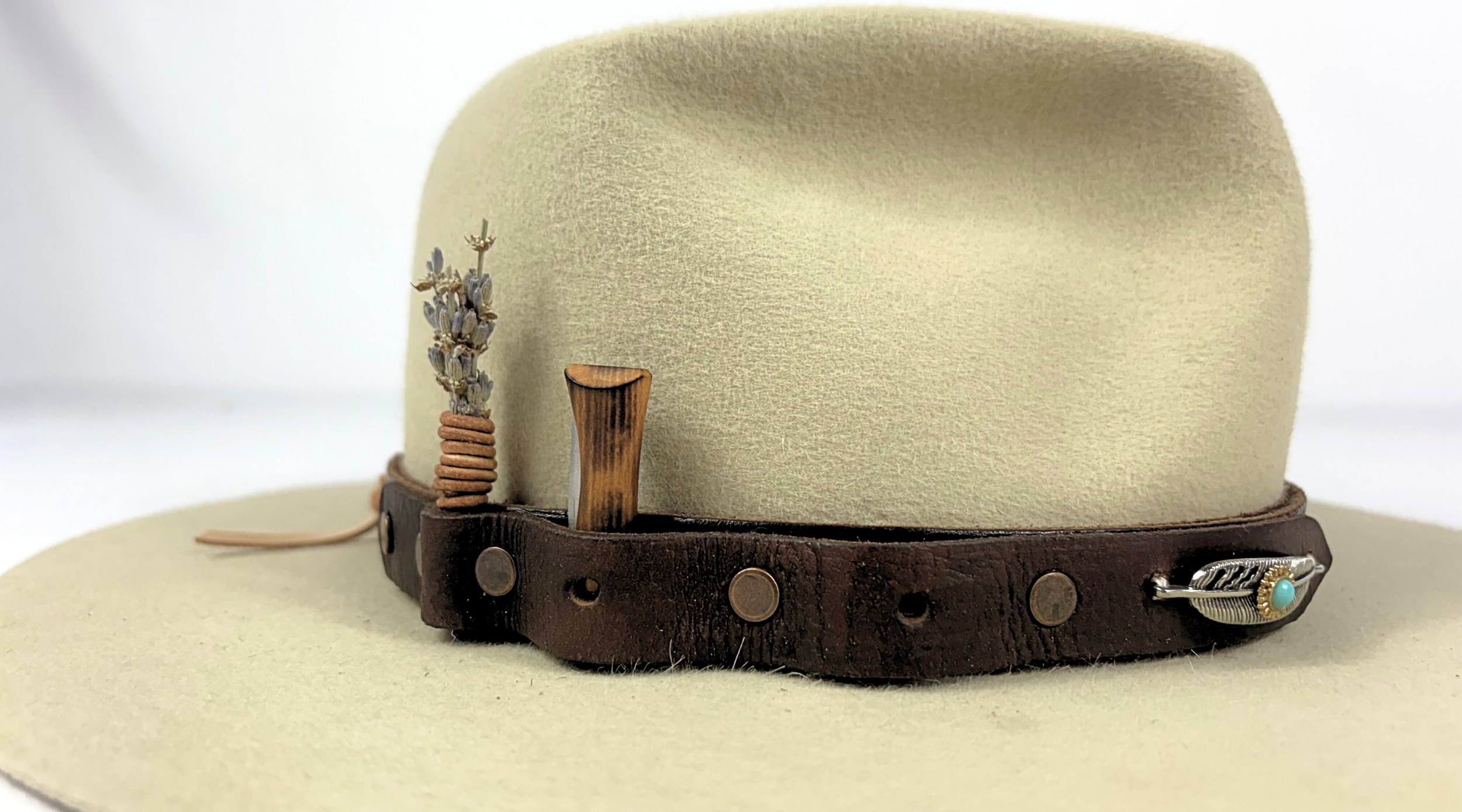 Beige cowboy hat with a brown leather band featuring decorative elements on a white background