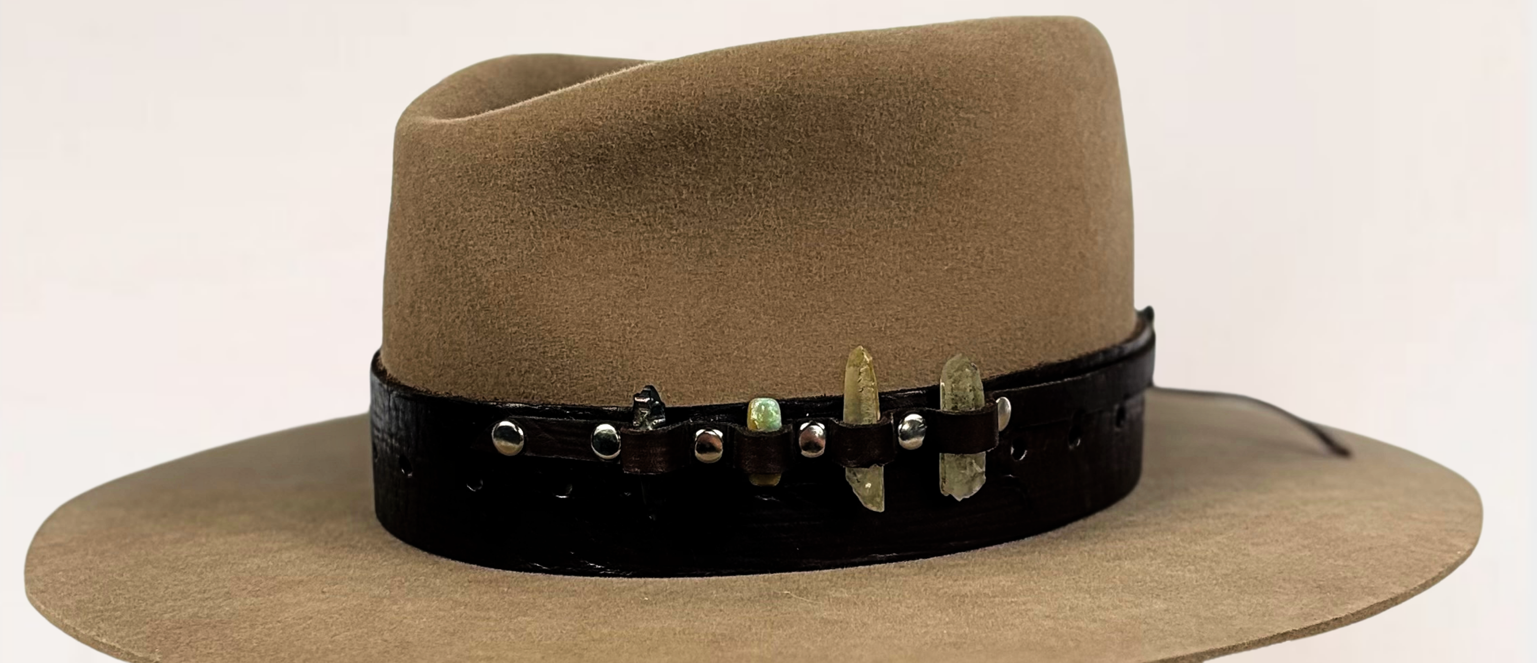 Brown fedora hat with a decorative band on a wooden block against a white background