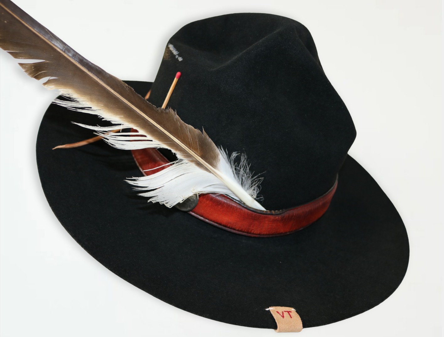 Black fedora hat with a red band and feather on a white background